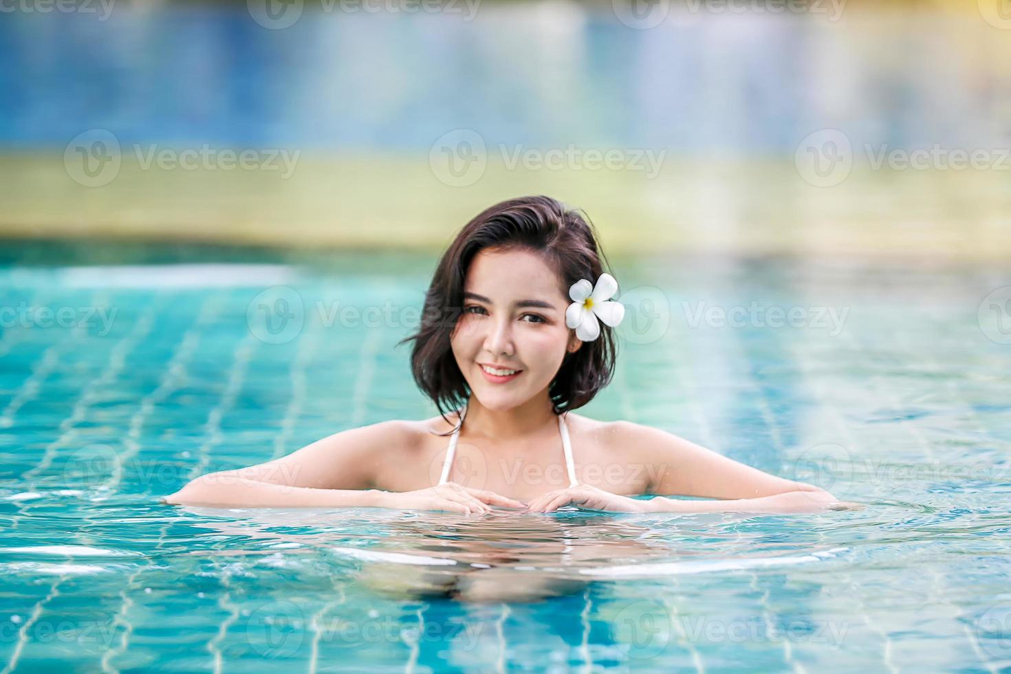 jovem desfrutando e relaxando à beira da piscina. modelo de jovem magro em biquíni branco à beira da piscina. foto