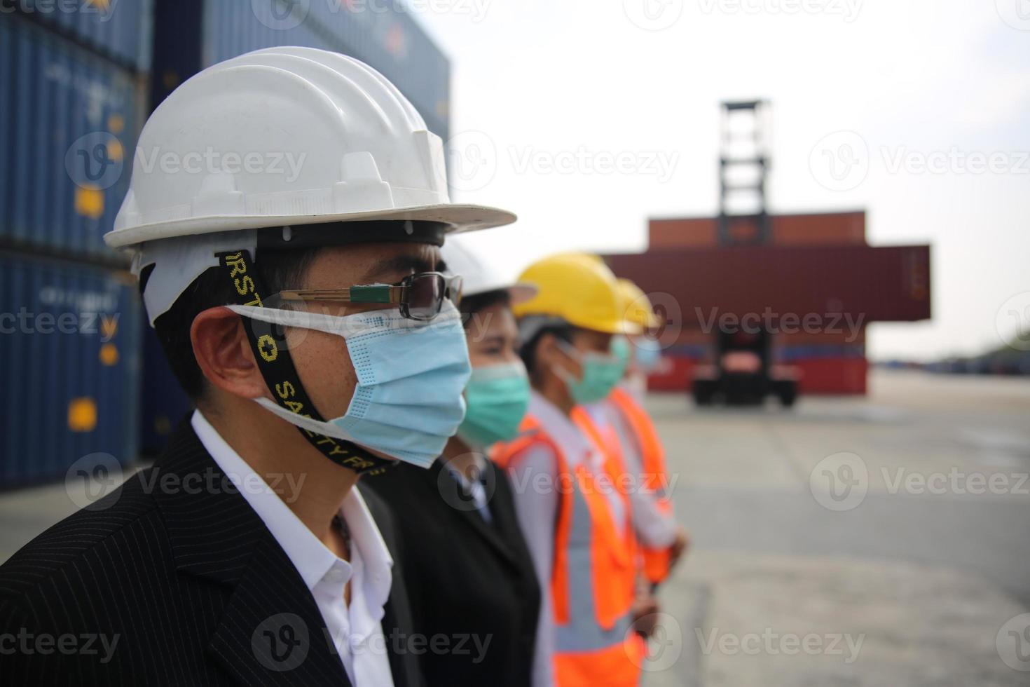 grupo de trabalhadores da indústria controla o carregamento de contêineres no terminal de contêineres, durante a verificação do covid-19. foto