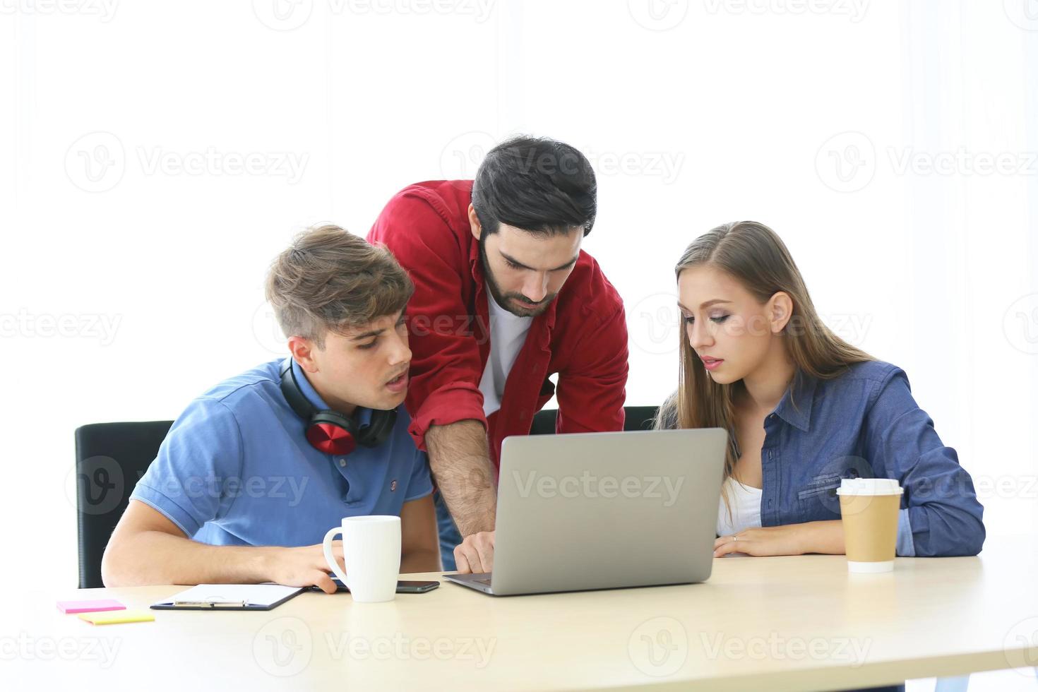 grupo diversificado de jovens empresários discutindo um projeto de trabalho enquanto estão sentados juntos em uma mesa em um escritório moderno. conceito de coworking foto