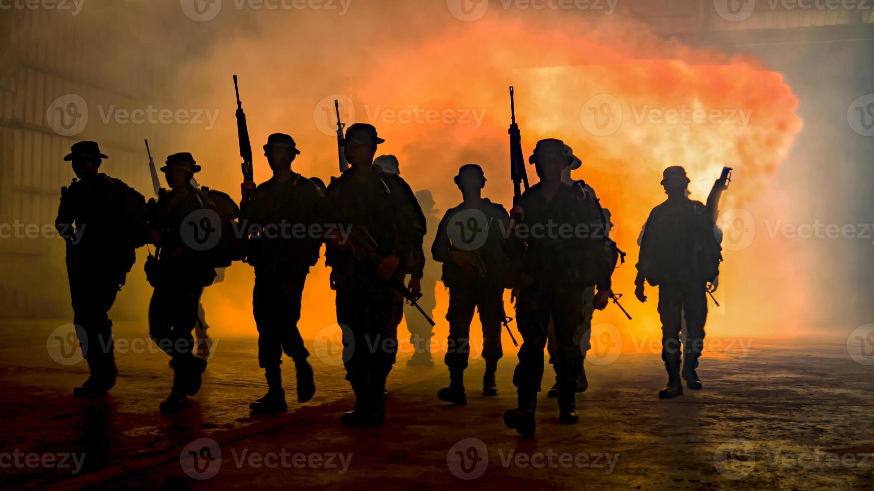 silhuetas de soldados do exército no nevoeiro contra um pôr do sol, equipe de fuzileiros navais em ação, cercado de fogo e fumaça, atirando com rifle de assalto e metralhadora, atacando inimigo foto