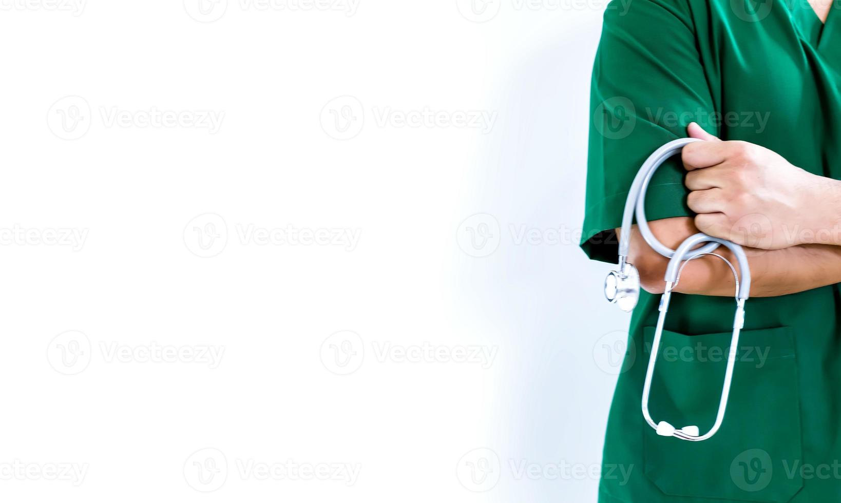 meio do médico gesticulando em pé contra a parede, médico com os braços cruzados segurando o estetoscópio foto