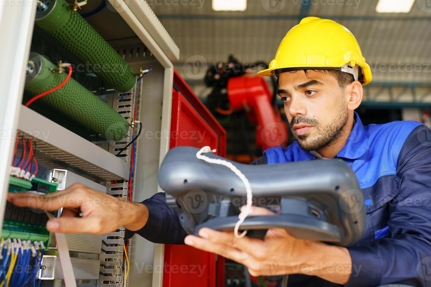 engenheiro industrial ou trabalhador usando um capacete em pé em uma fábrica industrial pesada. a manutenção procurando trabalhar em máquinas industriais e verificar a configuração do sistema de segurança na fábrica. foto