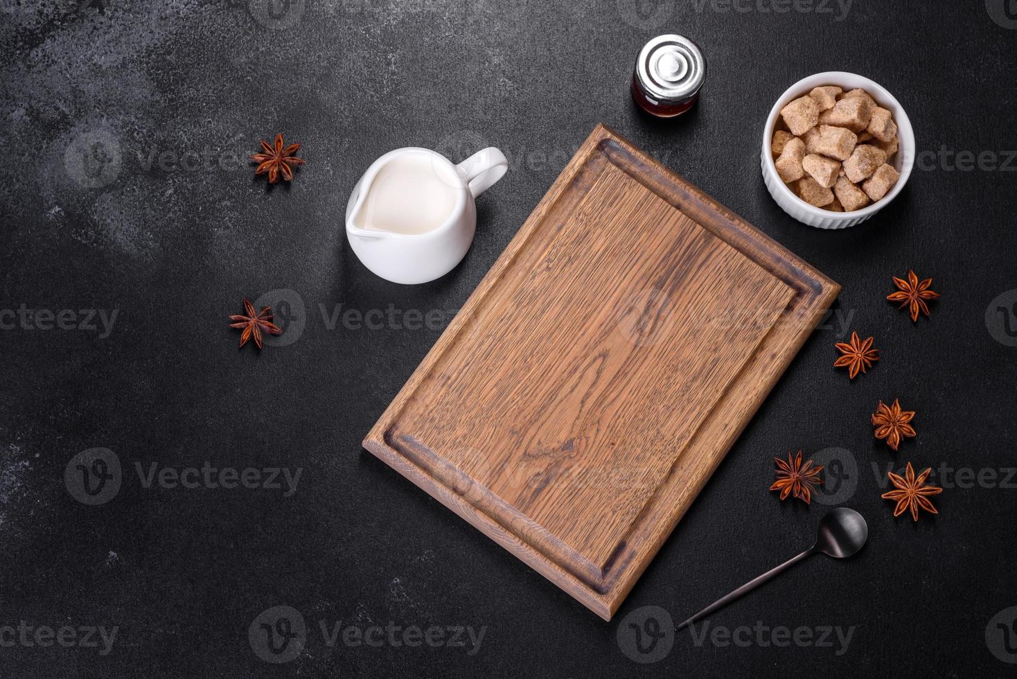 açúcar, canela e outras especiarias em uma tábua de madeira foto