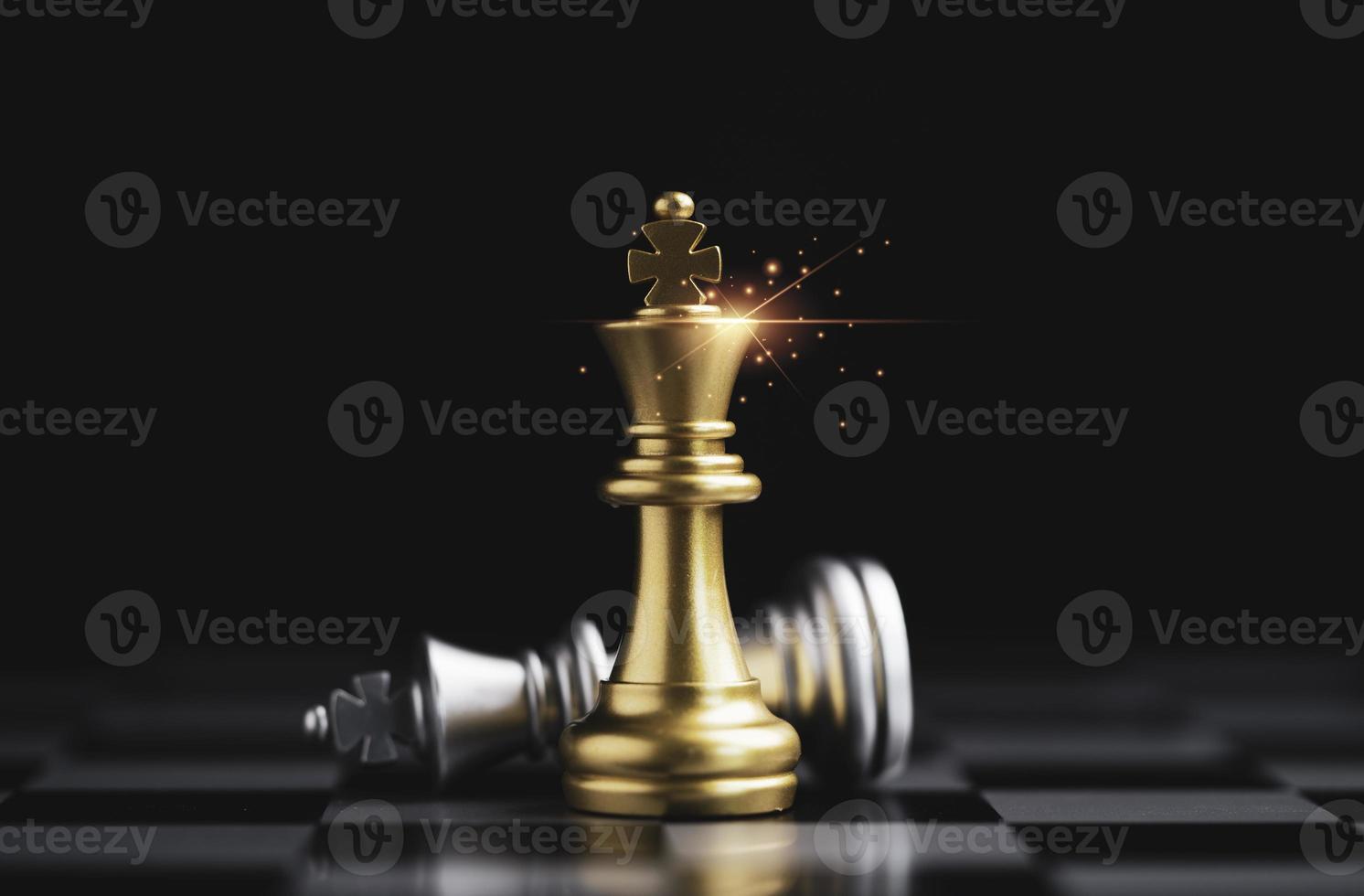 xadrez rei dourado em pé e xadrez rei prata caindo no tabuleiro de xadrez para o vencedor com o conceito de concorrente e estratégia de negócios. foto