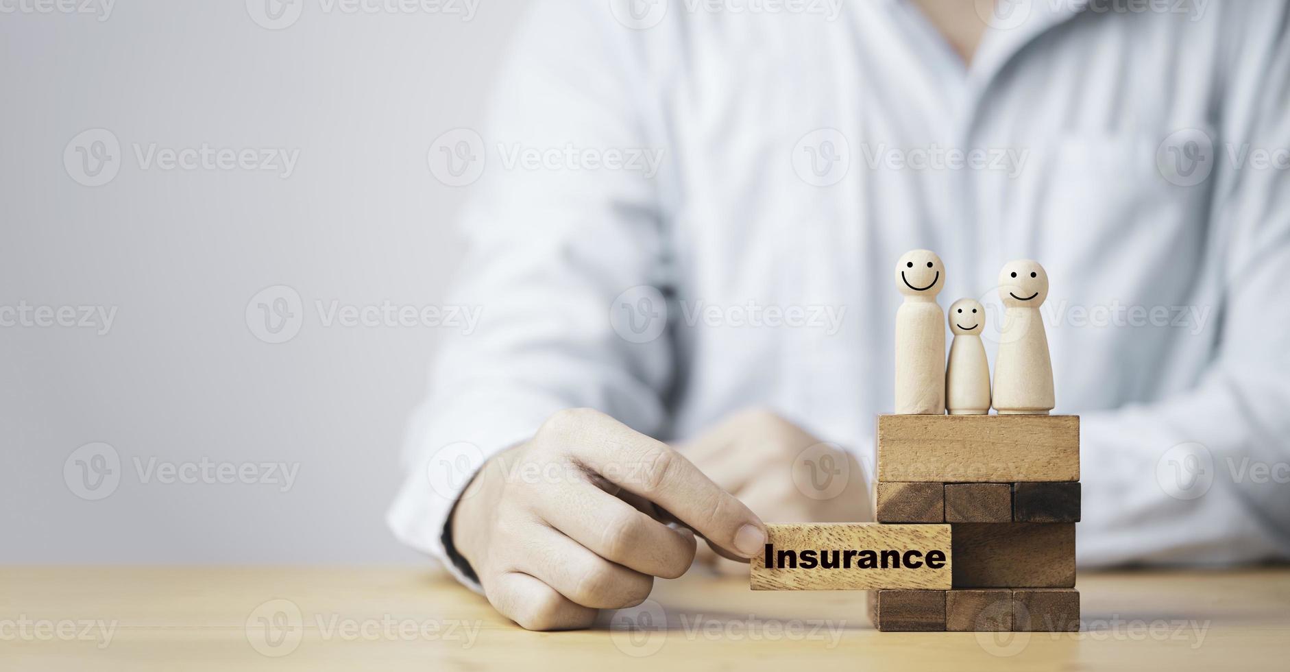 empresário retire o bloco de madeira que imprime o texto do seguro de tela com humano de madeira em cima para o seguro familiar para fazer o conceito de segurança de vida. foto