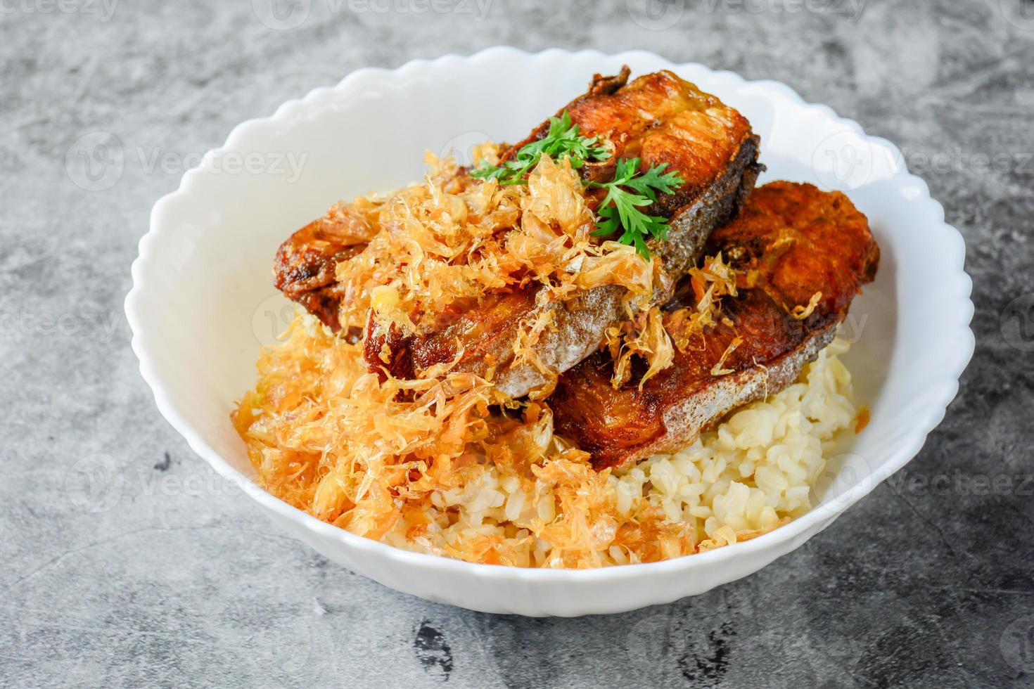 peixe pangasius fatiado frito com alho, servido com arroz integral. foto