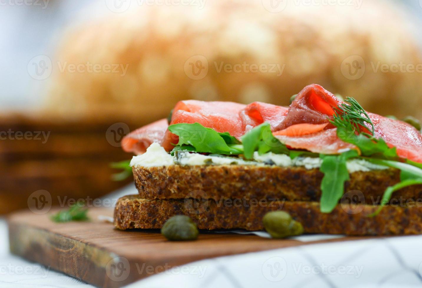 sanduíche de salmão defumado com queijo, pistache e folhas de salada, pães integrais foto