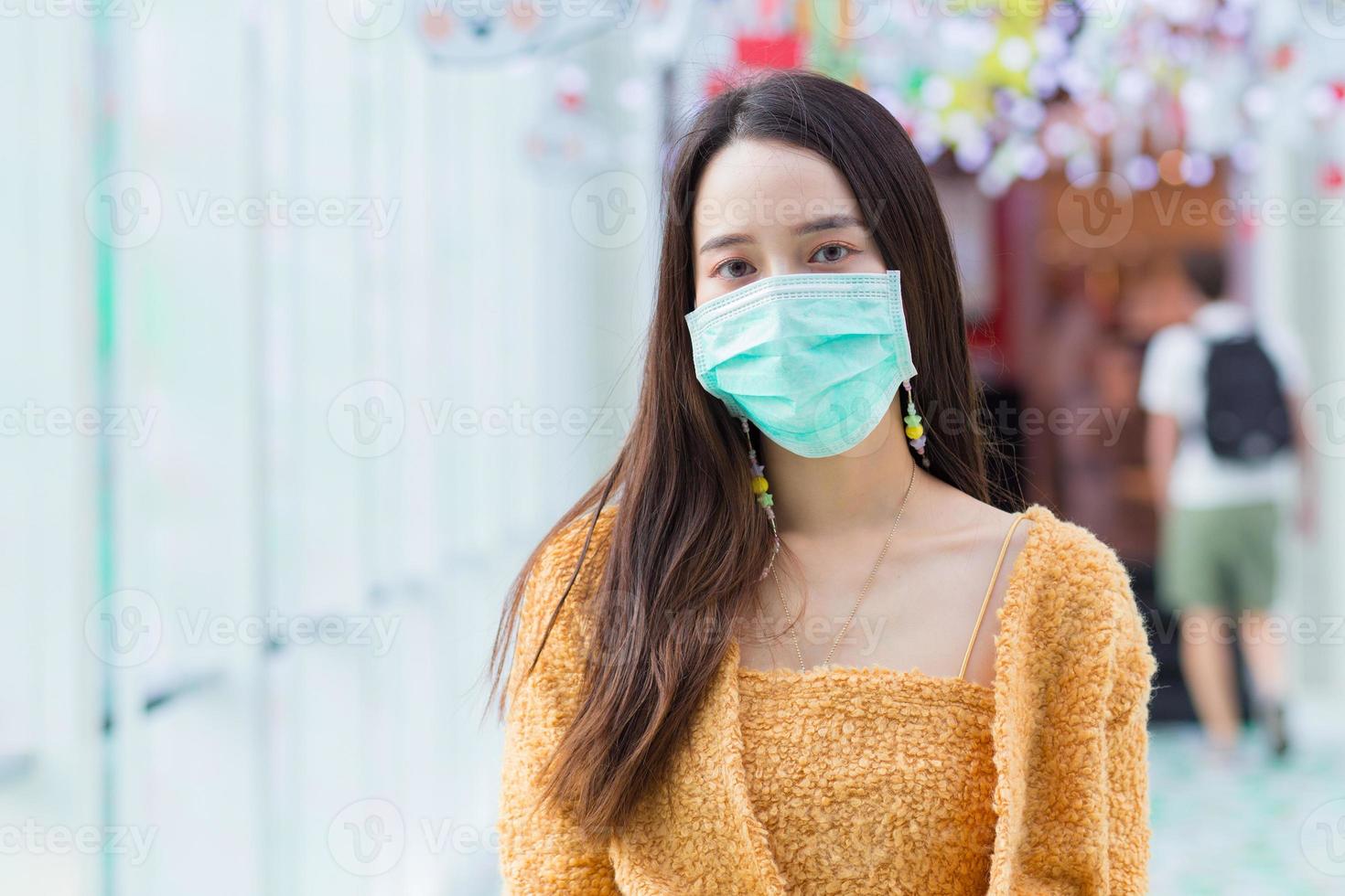 mulher asiática com cabelo comprido usa malha laranja e máscara facial médica em cuidados de saúde, novo conceito normal. foto
