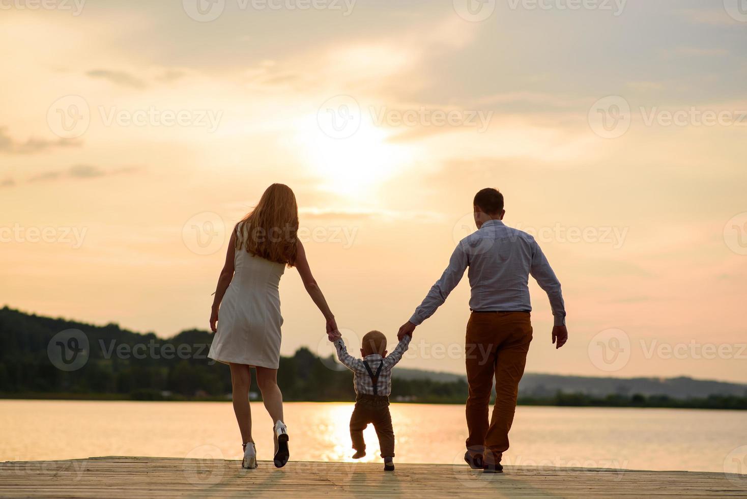 pai e mãe levam o filho de um ano pela mão. foto