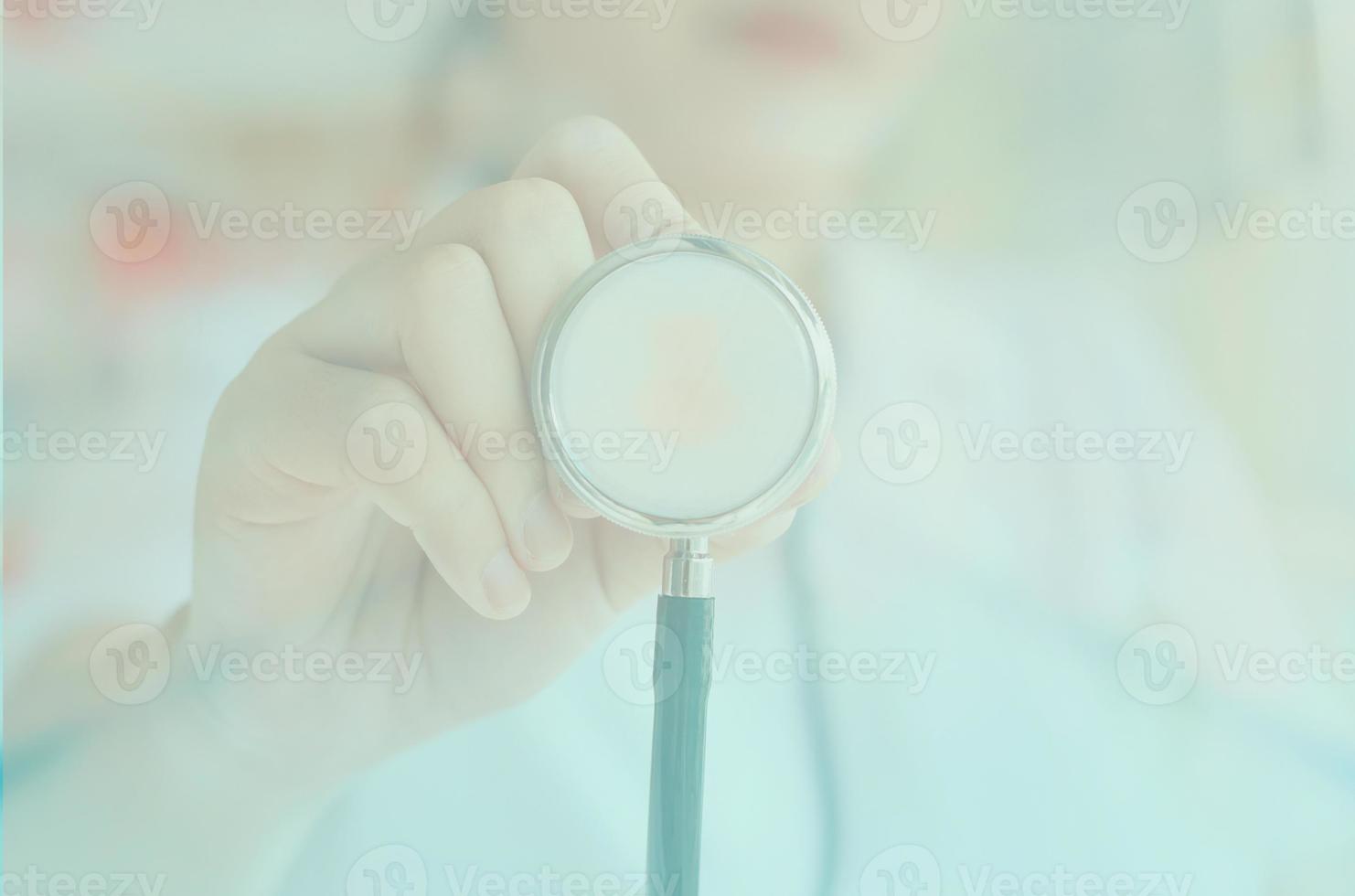 médica de uniforme branco segurando o estetoscópio foto