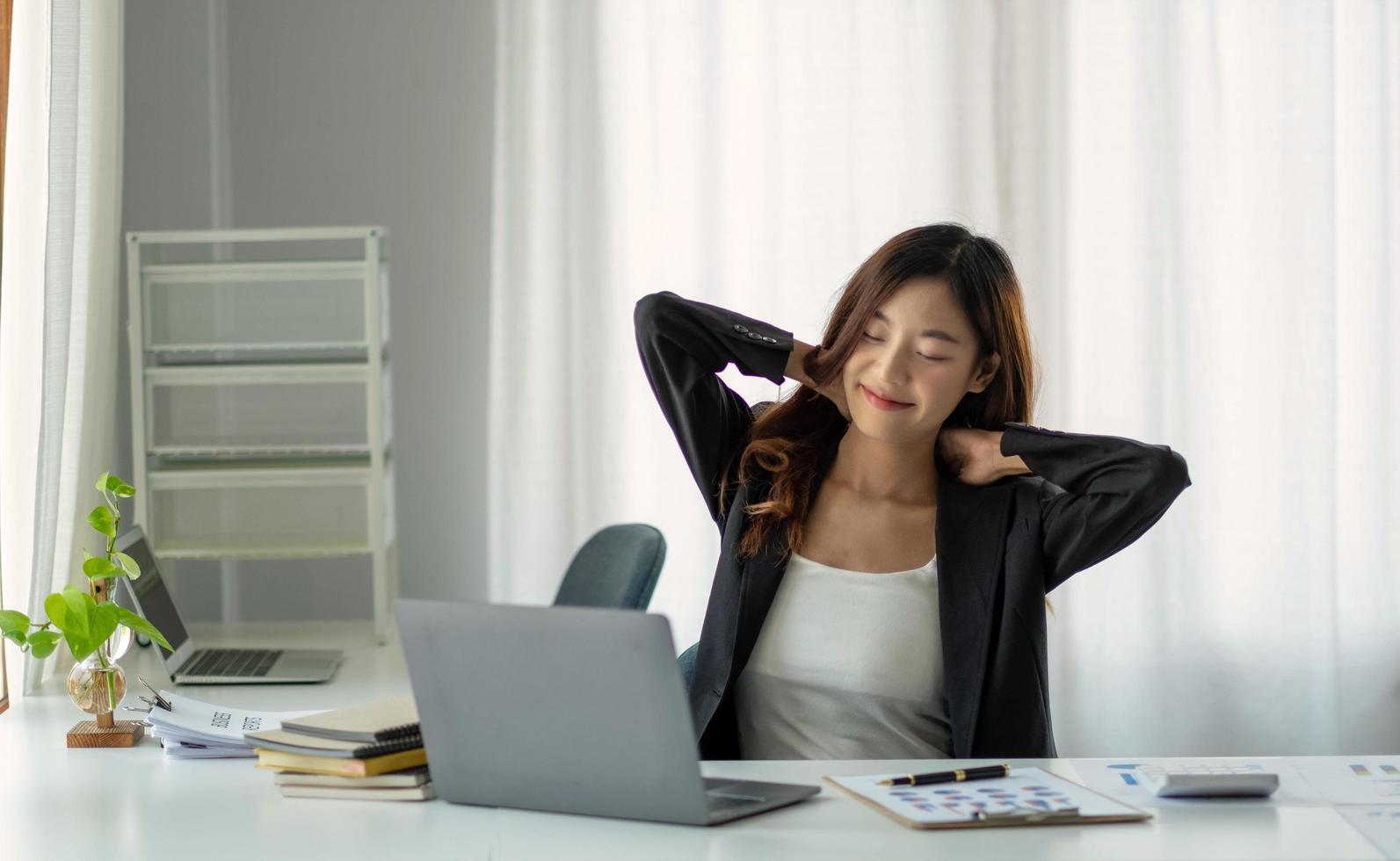 jovem empresária asiática esticando os braços levantados relaxando no escritório. foto