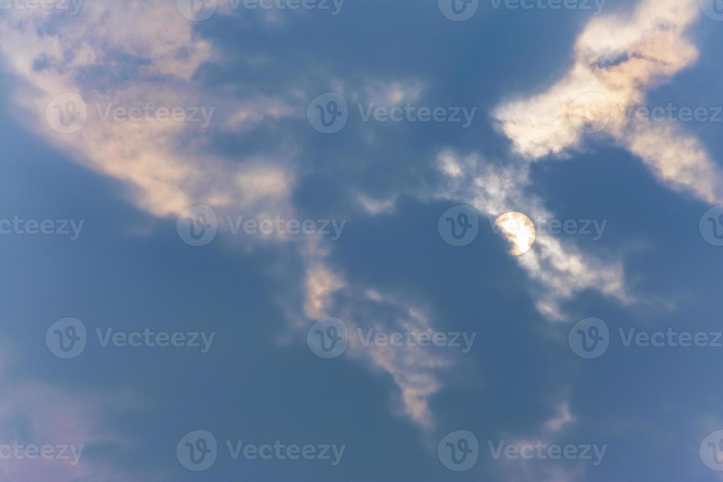foto de close-up de céu azul nublado no meio-dia, com sol coberto pela nuvem