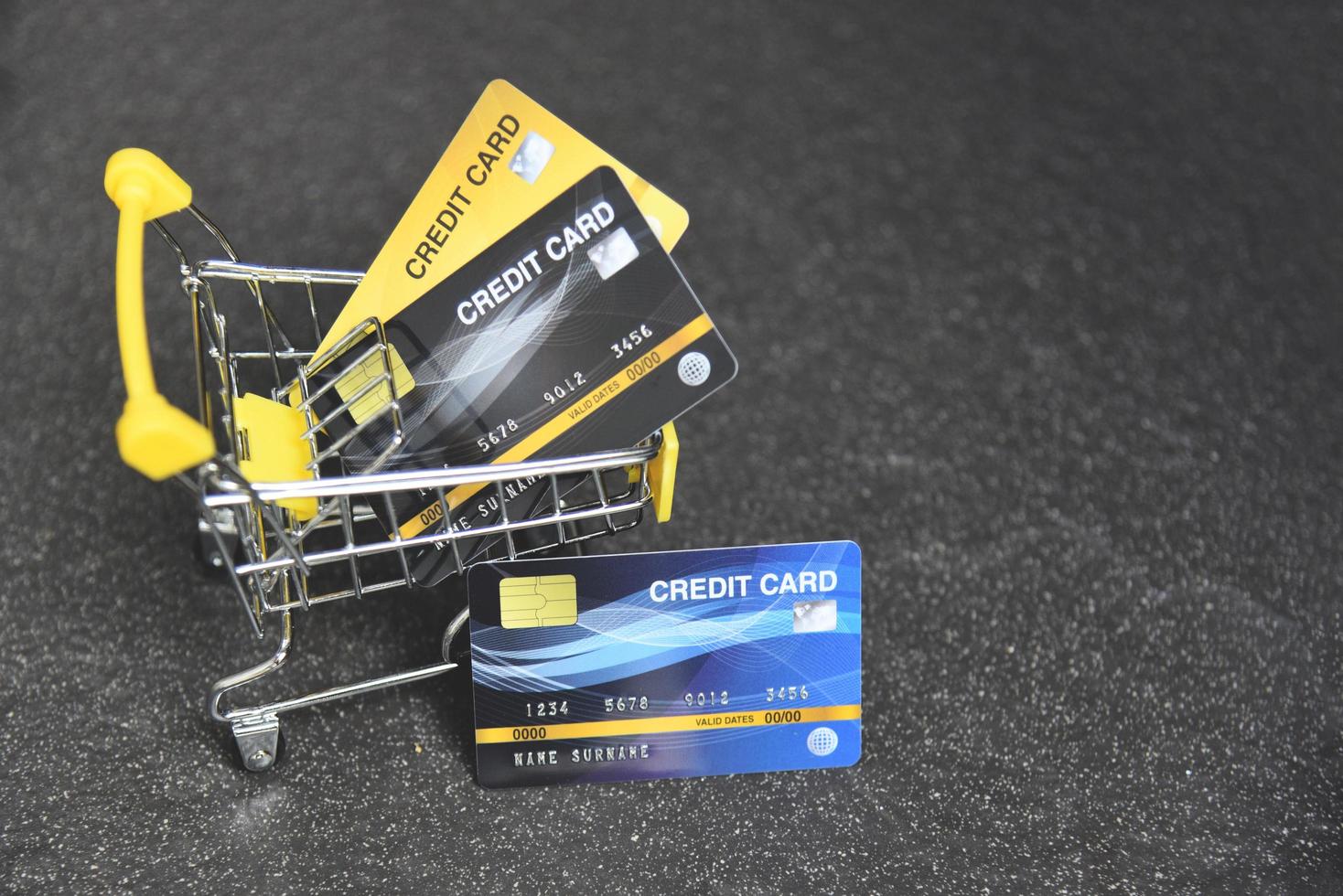 compras online com cartão de crédito em um carrinho de compras no fundo escuro para pagamento online em casa foto