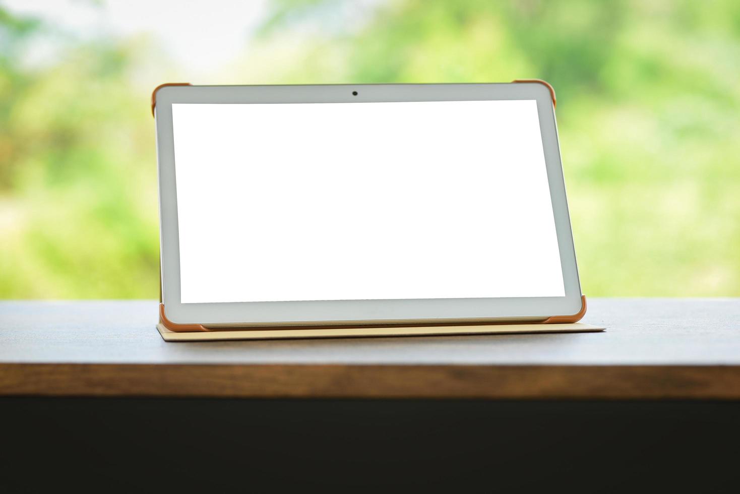 tablet na tela isolada da mesa - computador digital tablet ou tela em branco do laptop na mesa natureza fundo verde foto