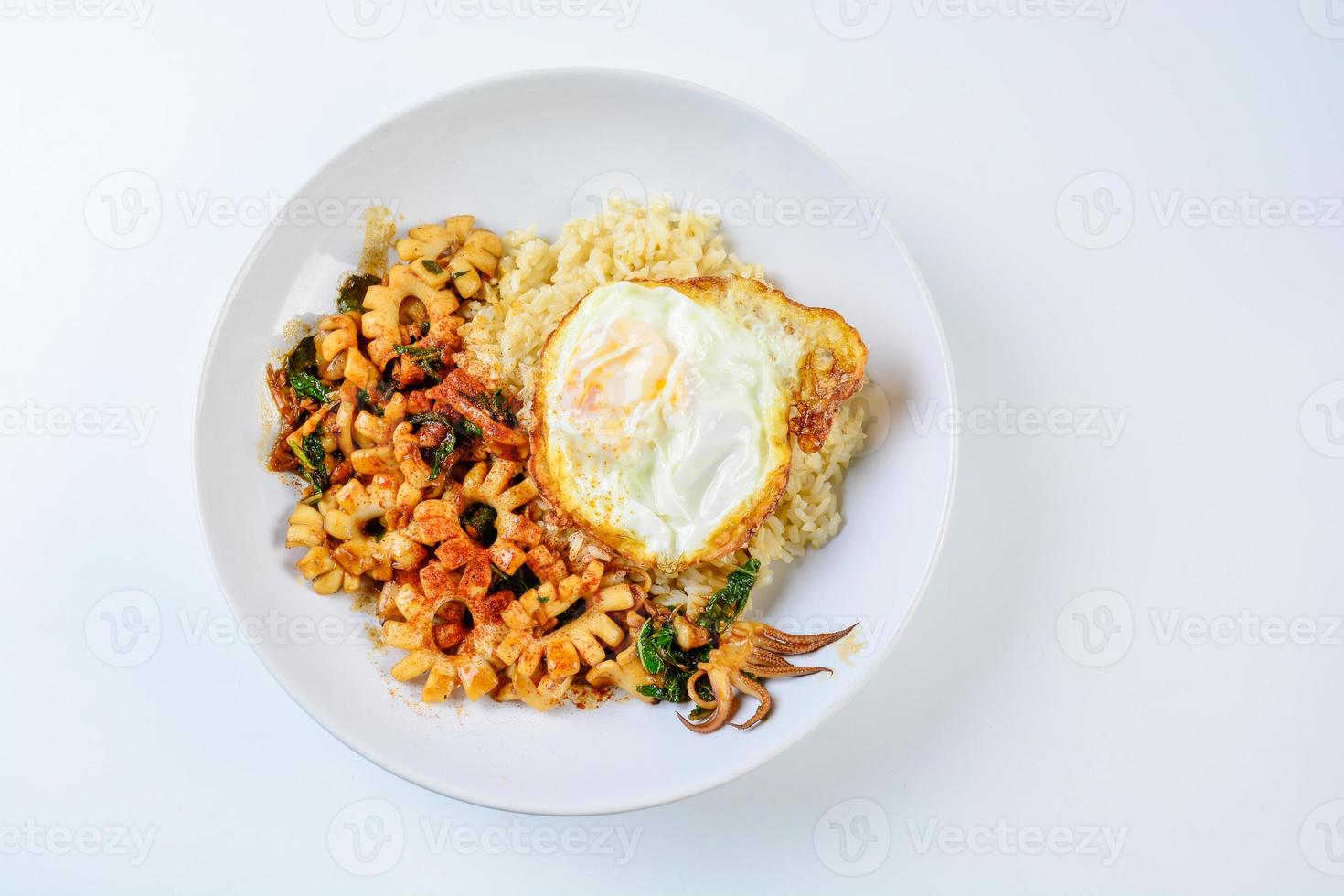 lula frita apimentada com folhas de manjericão e pimenta, ovo frito, servido com arroz integral. prato quente e picante. foto