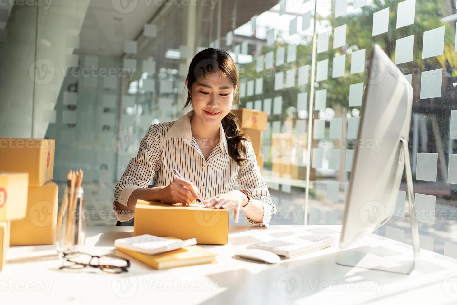 iniciando pequenas empresas donas de pme empresárias escrevem o endereço na caixa de recebimento e verificam os pedidos on-line para se preparar para embalar as caixas, vender aos clientes, pme idéias de negócios on-line. foto