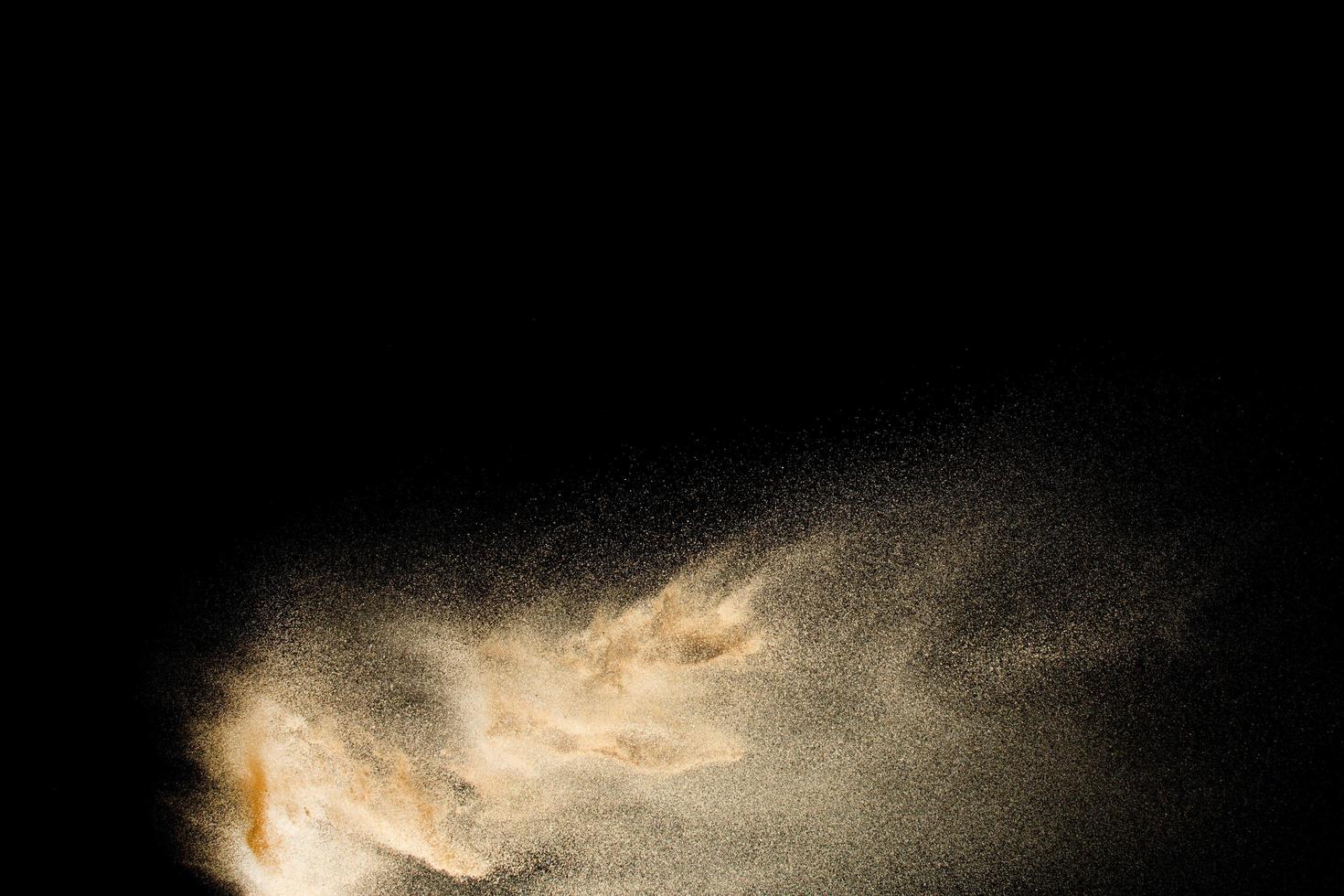 respingos de areia de cor marrom contra um fundo escuro. explosão de areia seca do rio isolada no fundo preto. nuvem de areia abstrata. foto