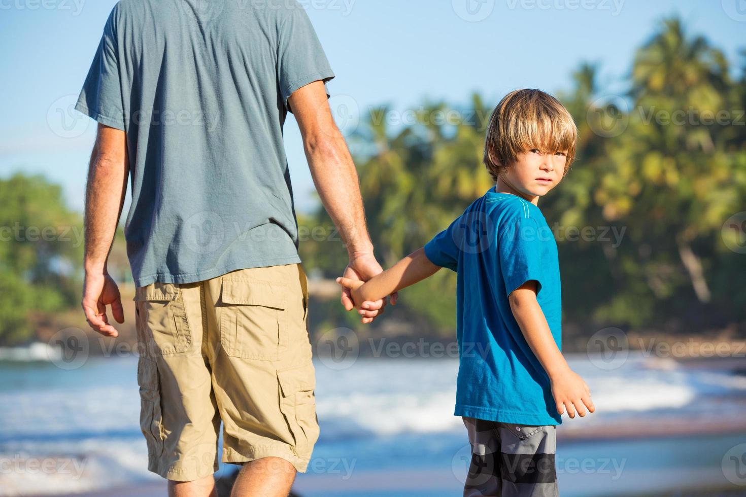 feliz pai e filho caminhando juntos na praia foto