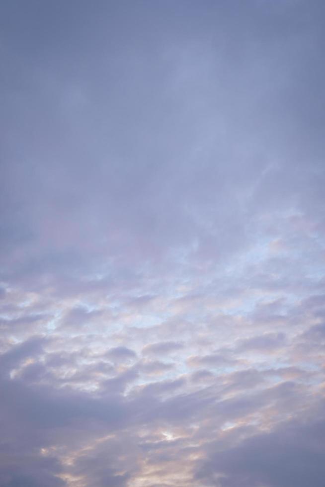 imagem vertical de nuvens do sol com céu azul à noite. foto