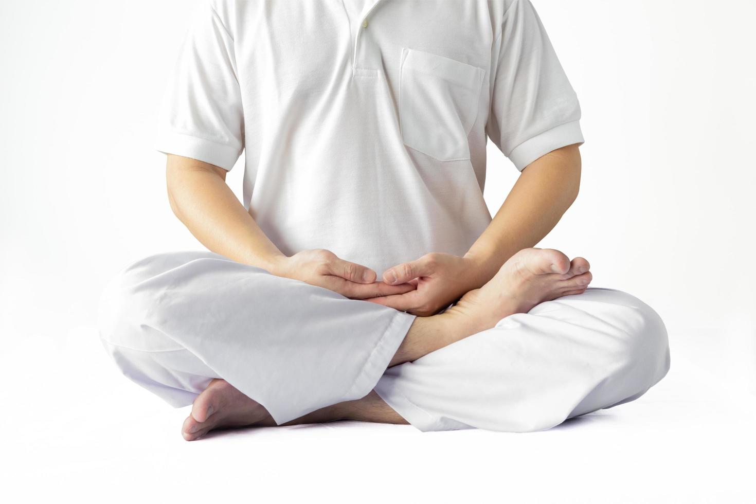 um homem de túnica branca meditando contra um pano de fundo branco com um traçado de recorte. foto