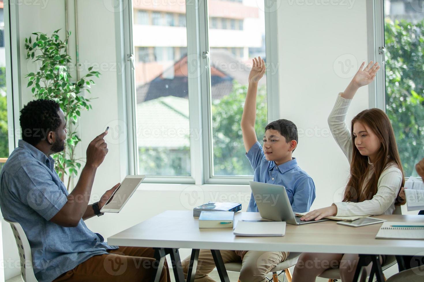 aluno levantando a mão com uma pergunta para o professor. professor apontando para o aluno com a mão levantada na sala de aula de ciências. foto