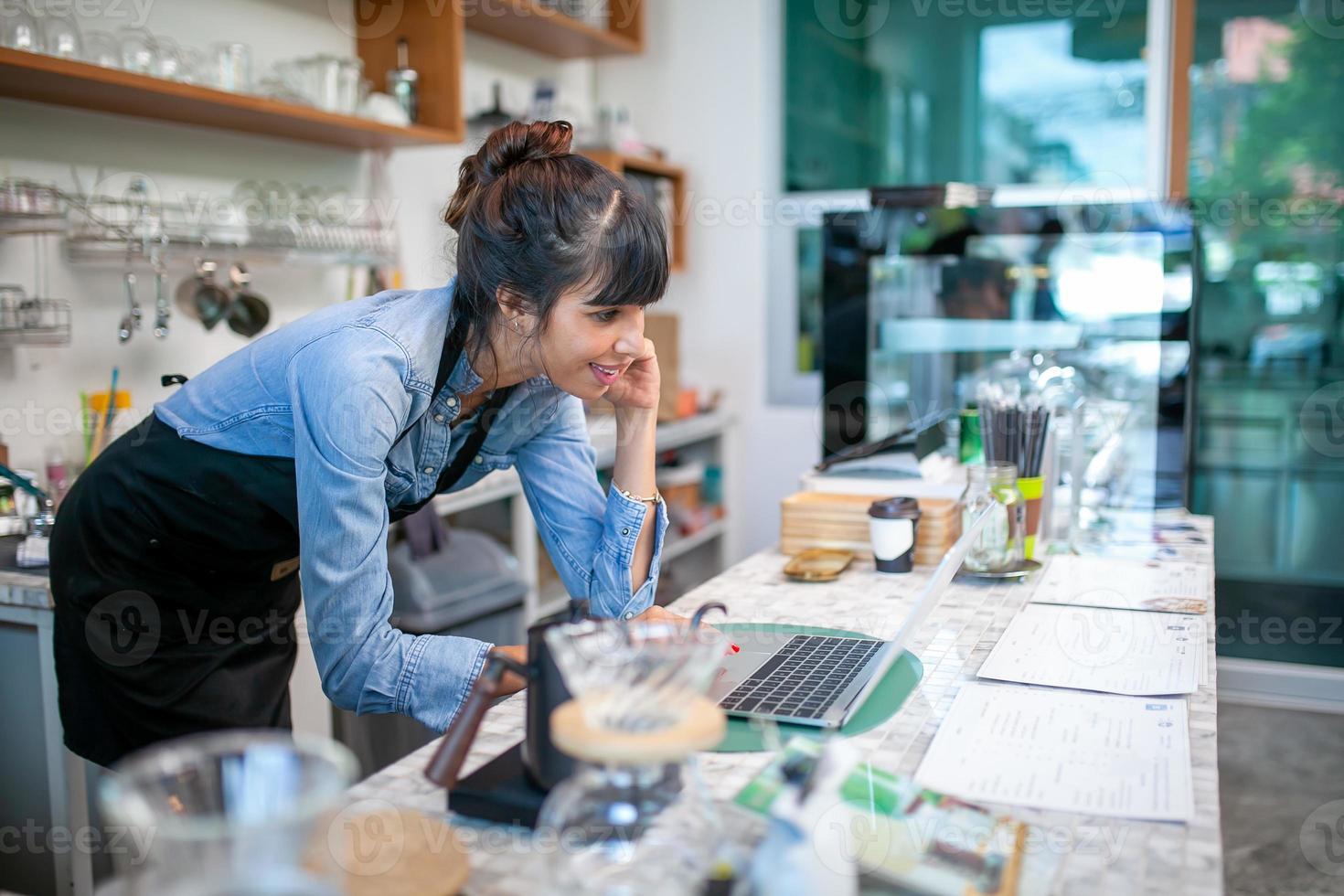 barista de homem feliz usando laptop para receber o pedido do cliente na cafeteria. foto