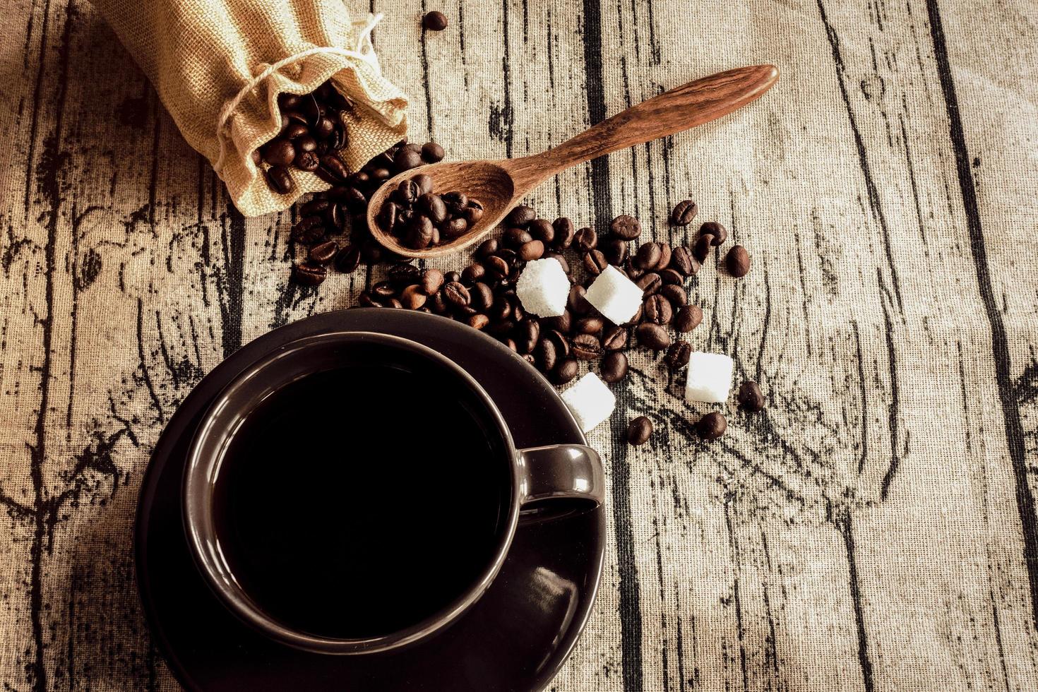 xícara de café com feijão em um tecido de linho de mesa de madeira. foto