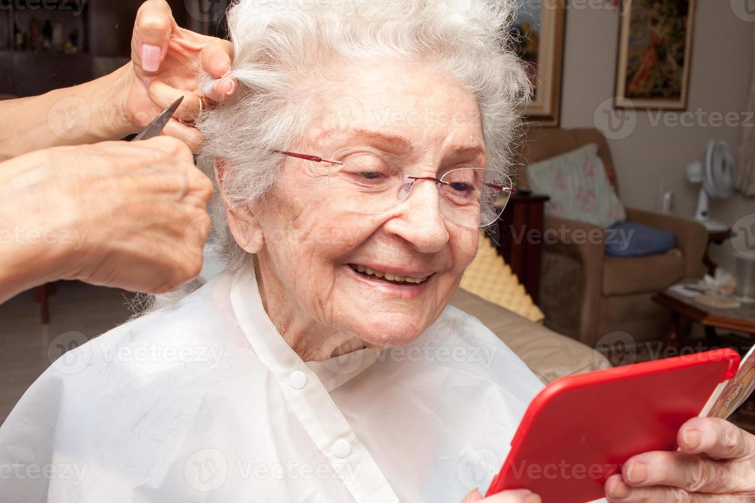 senhora idosa cortando o cabelo no conforto de sua casa foto