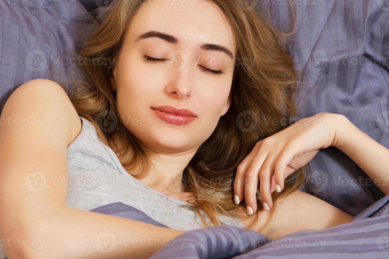 mulher jovem e atraente sorriso dormindo no quarto. vida saudável foto