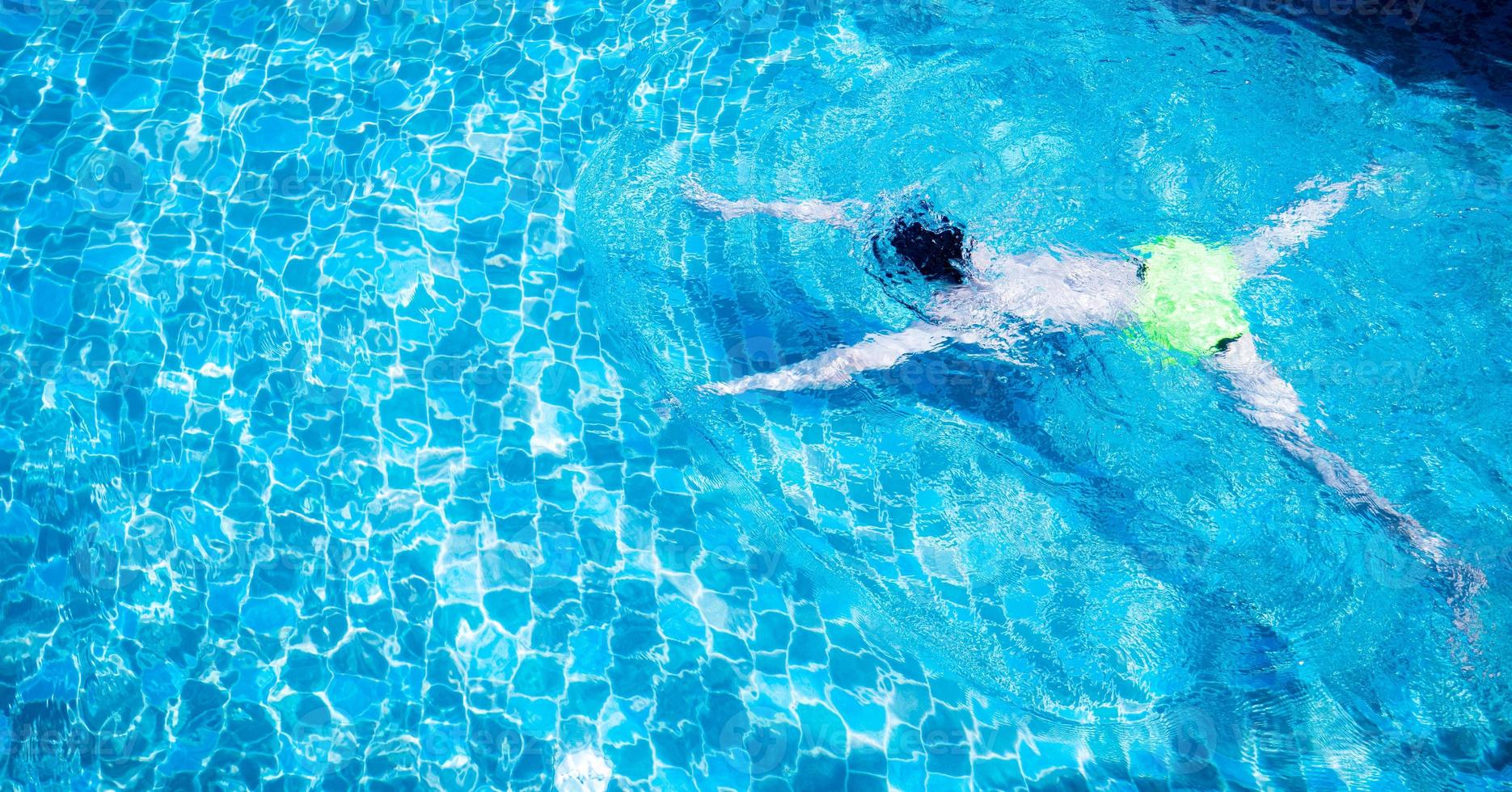 os homens estão nadando ou mergulhando na piscina. jovem exercitando ou relaxando na piscina ao ar livre. foto