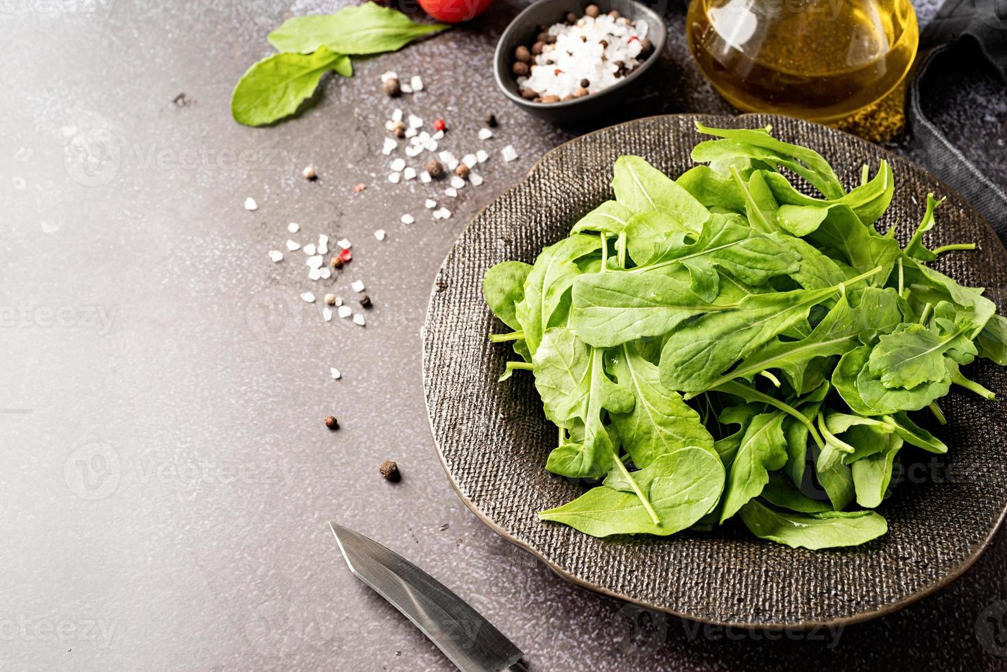 folhas de rúcula fresca em tigela preta com legumes frescos, copie o espaço foto