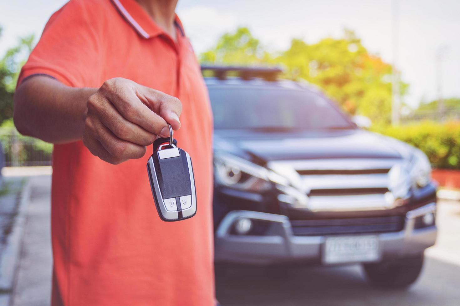 homem segurando as chaves do carro com carro no fundo foto