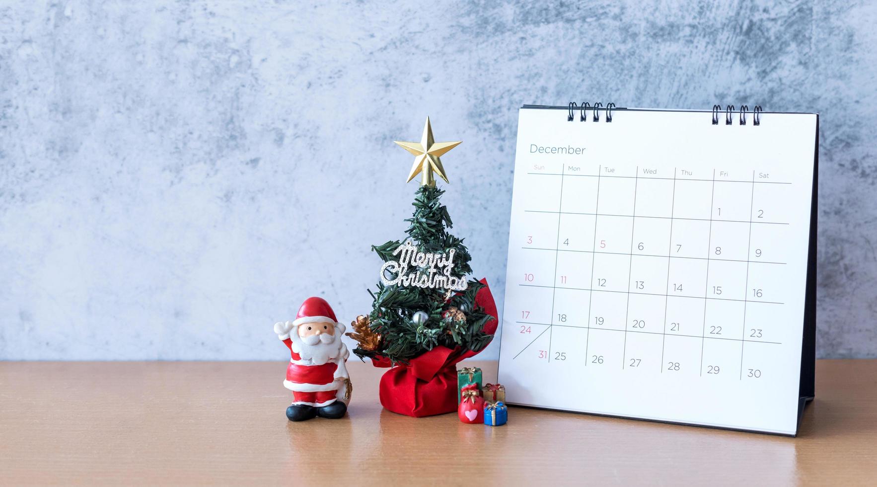 calendário de dezembro e decoração de natal - papai noel, árvore e presente na mesa de madeira. natal e feliz ano novo conceito foto