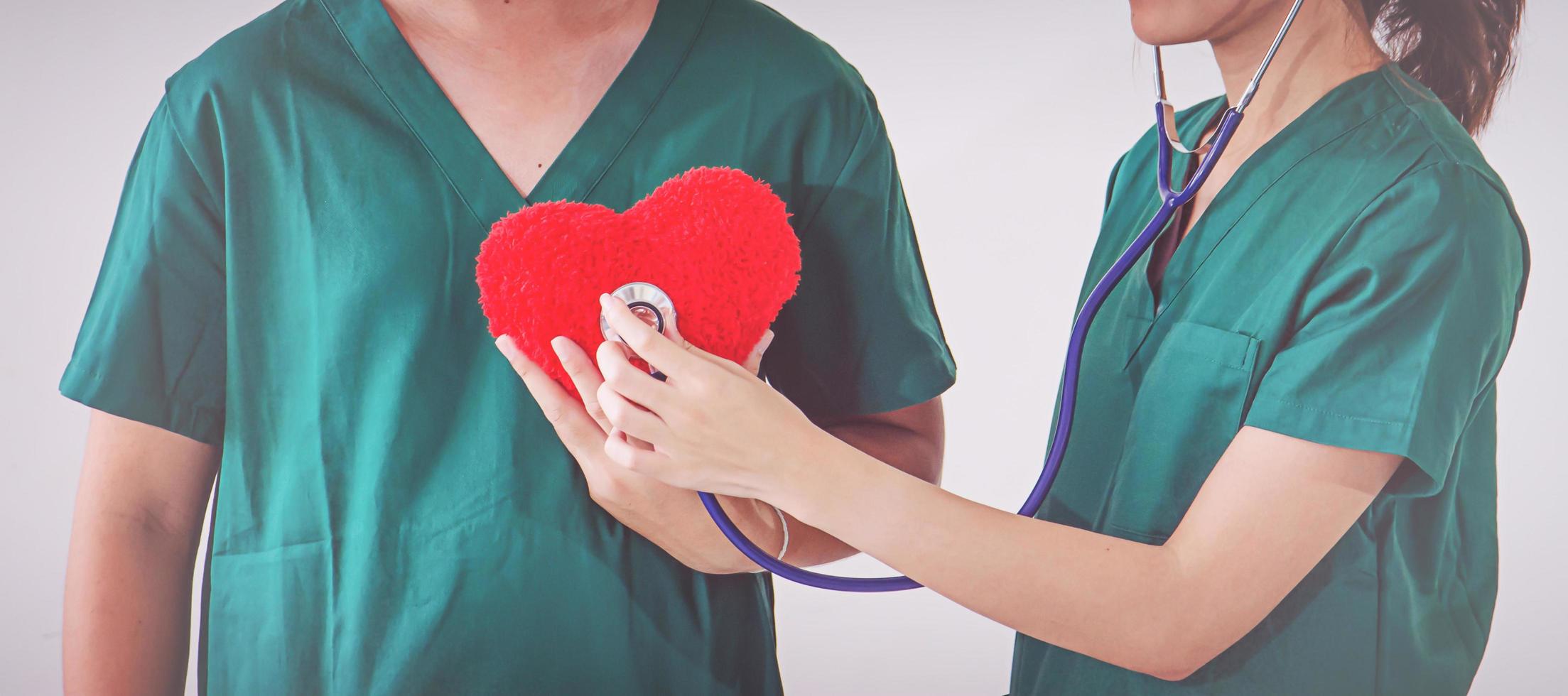 médico com estetoscópio examinando coração vermelho foto