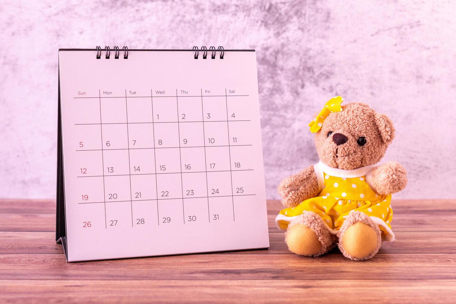 ursinho de pelúcia com calendário na mesa de madeira. comemoração do dia dos namorados foto