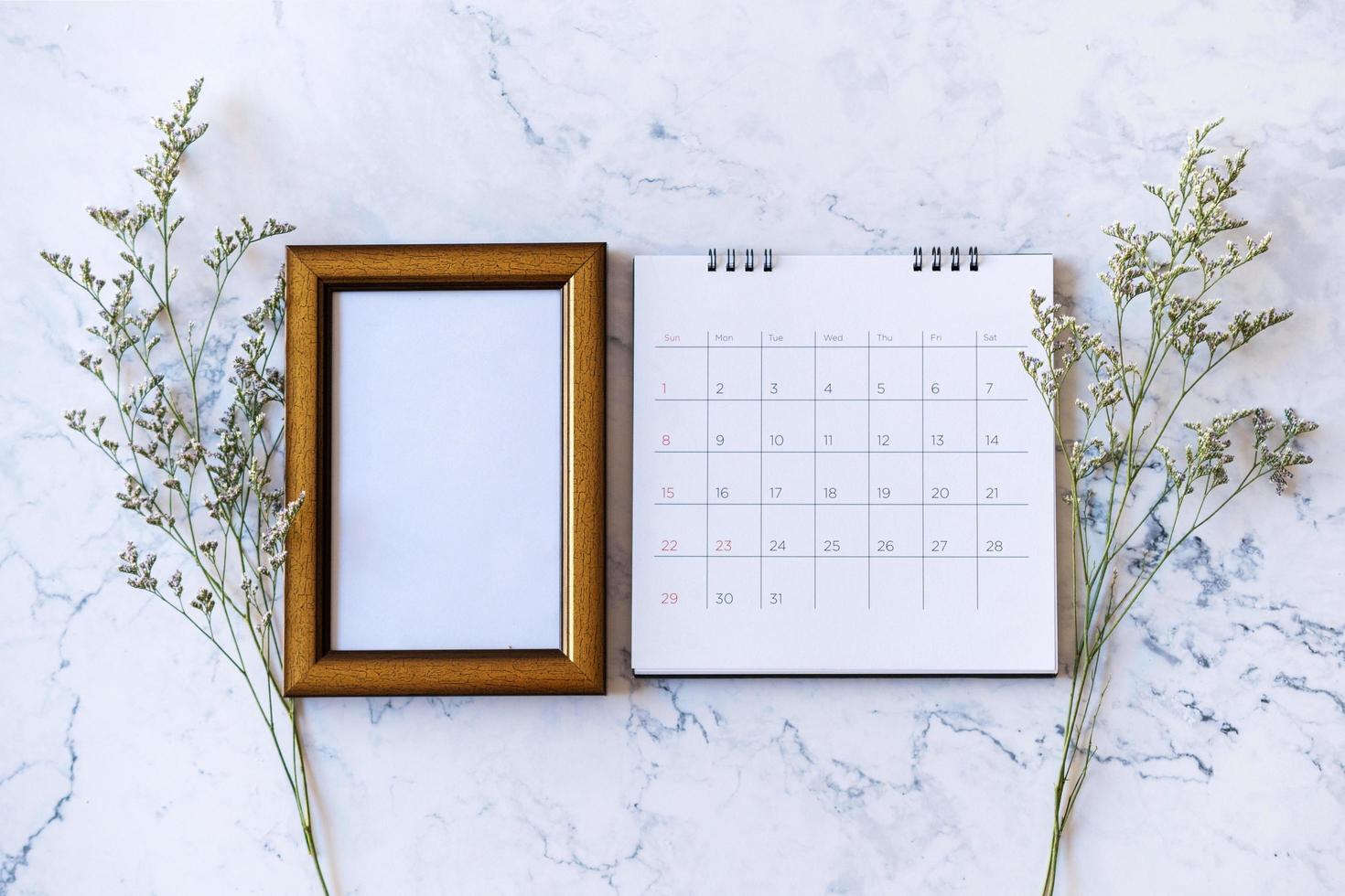 porta-retrato e calendário e flor de caspia no fundo de mármore foto