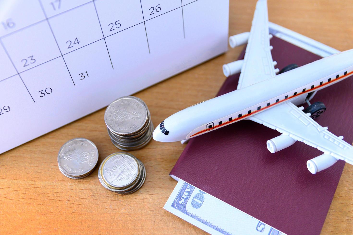 modelo de avião com calendário de papel na mesa de madeira. plano de viagem foto