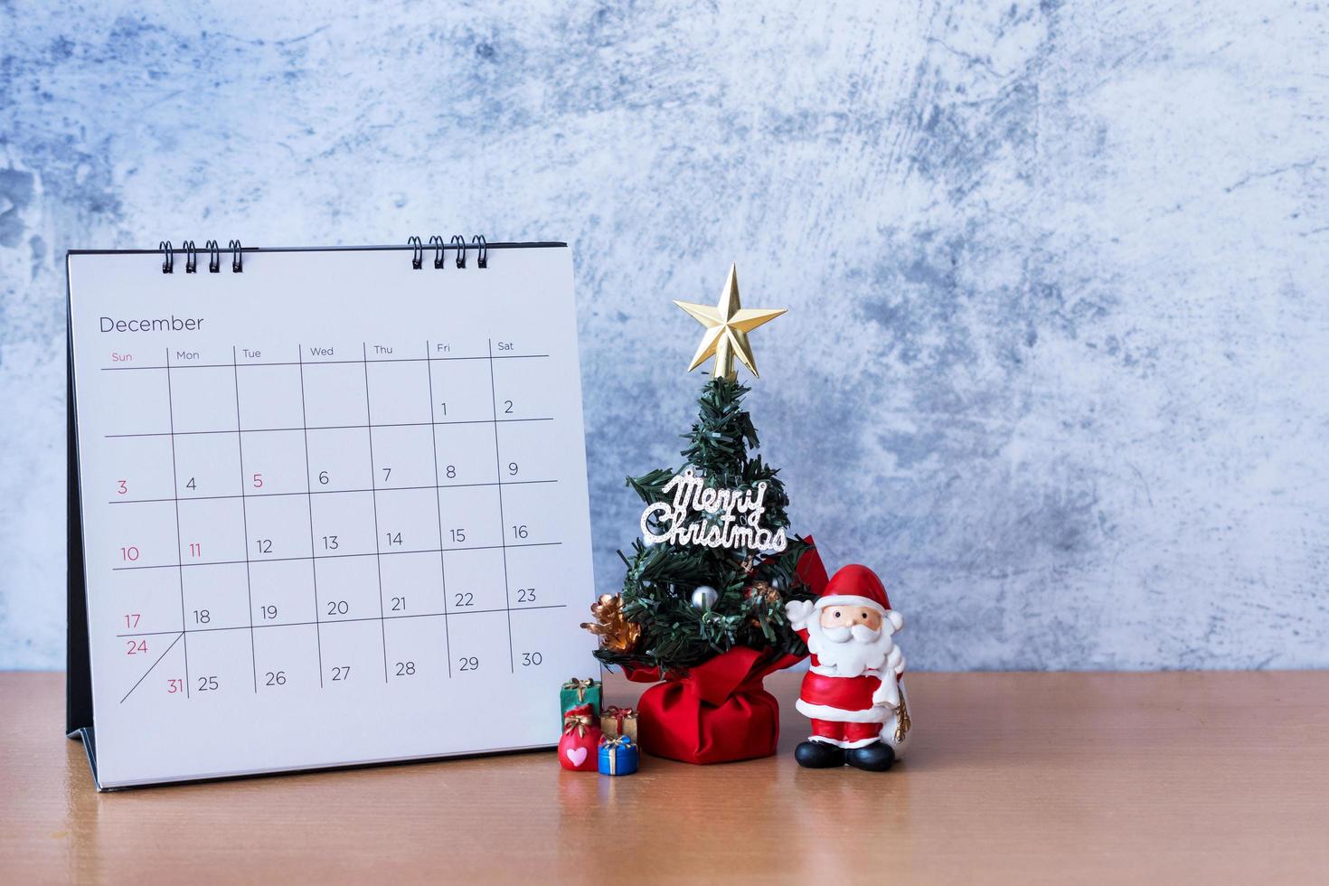 calendário de dezembro e decoração de natal - papai noel, árvore e presente na mesa de madeira. natal e feliz ano novo conceito foto