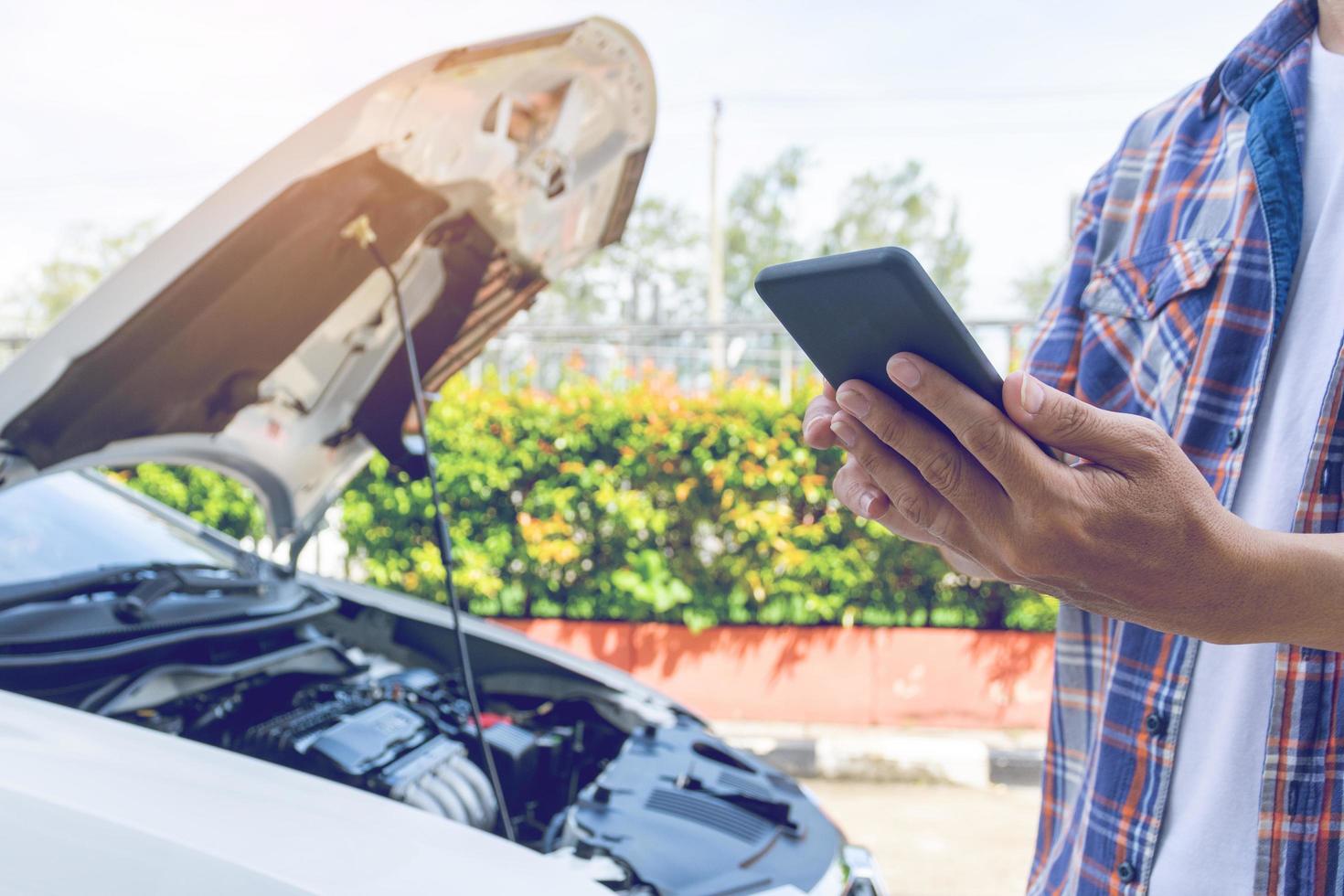 homem da ásia fica na frente de um carro quebrado pedindo ajuda foto