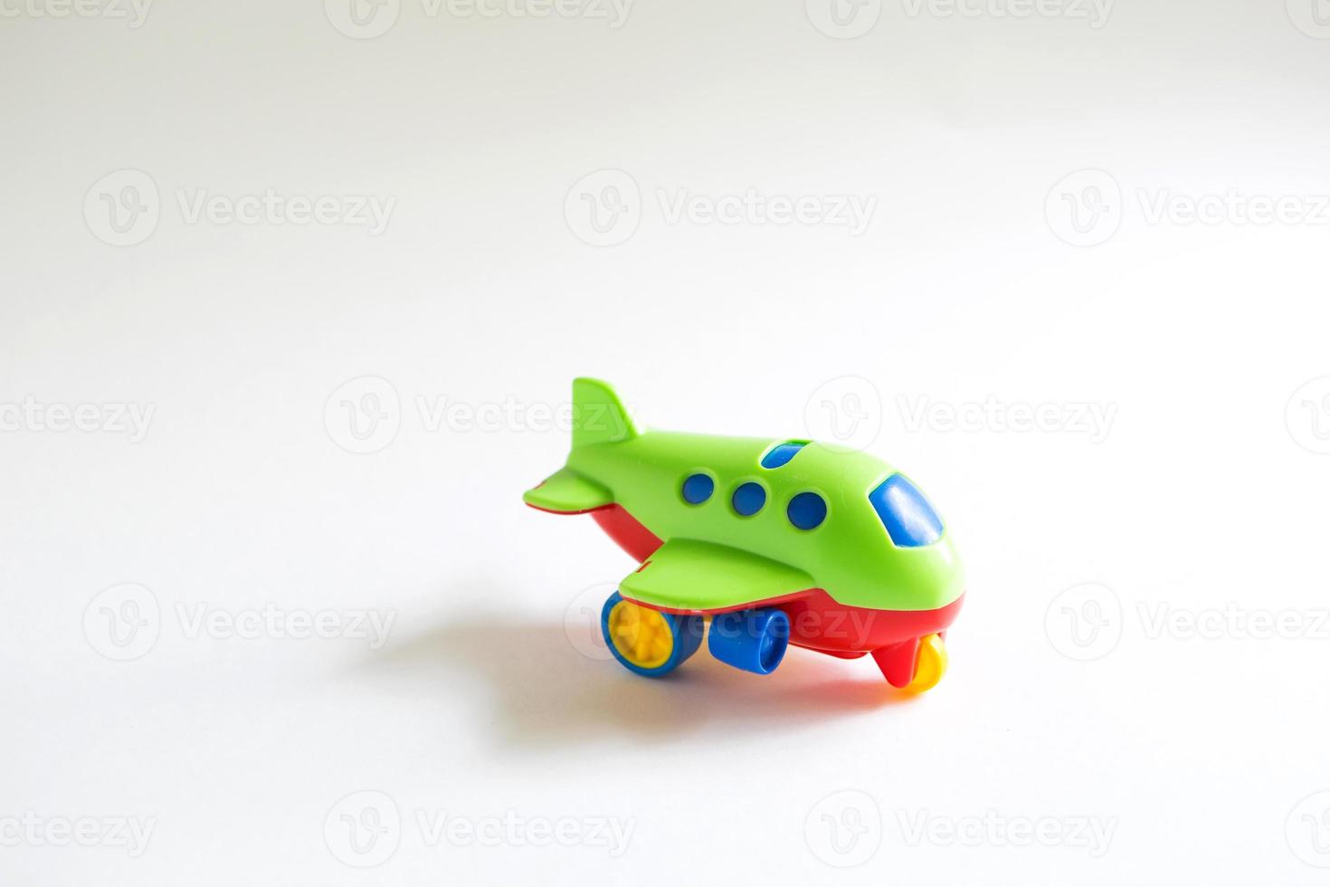 avião de plástico verde de brinquedo com detalhes coloridos de vermelho, azul e amarelo em um fundo branco. brinquedo para uma criança, o conceito de turismo e viagens, viagens aéreas. espaço para texto foto