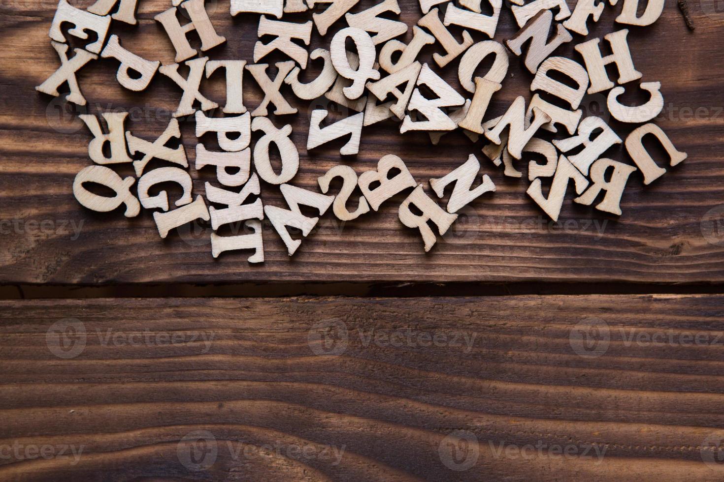 letras do alfabeto inglês em um fundo escuro de madeira. o conceito de educação, jogos de palavras, bordado. espaço para texto foto