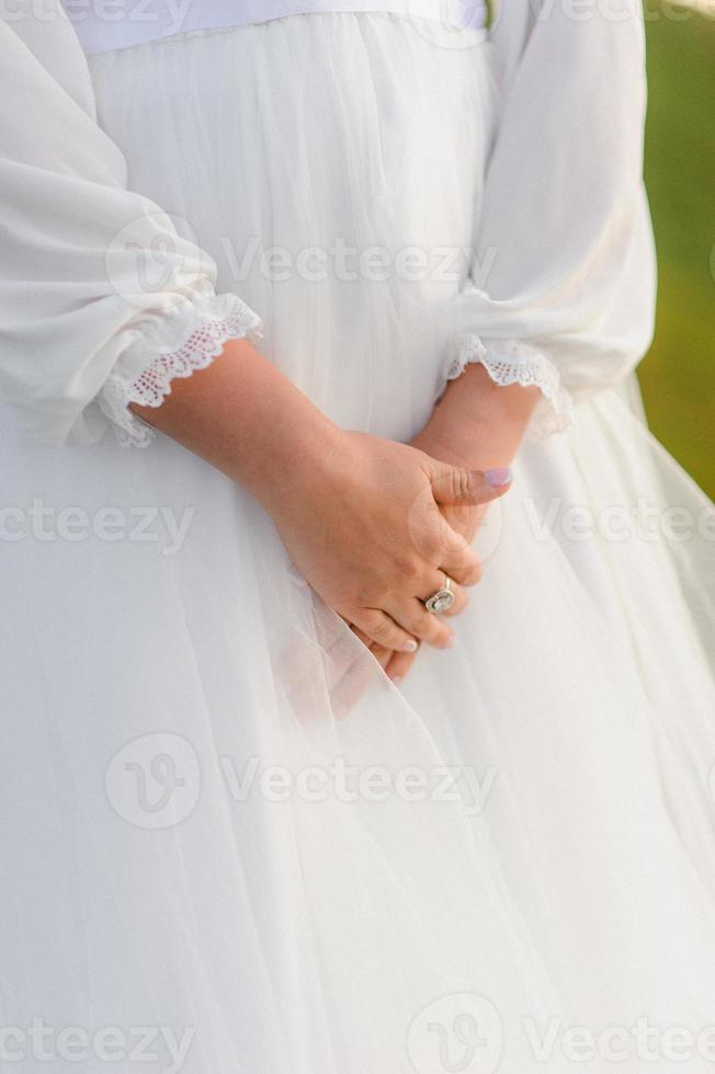 costureira abotoando o lindo vestido de noiva, elegante e de costas nuas. foto