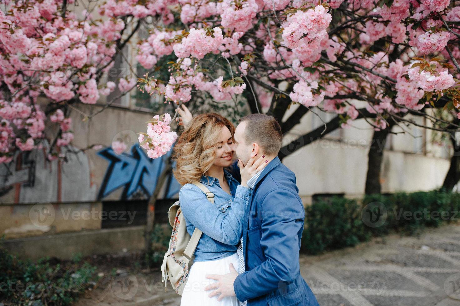 casal apaixonado em um pomar de macieiras florescendo deitado no cobertor foto