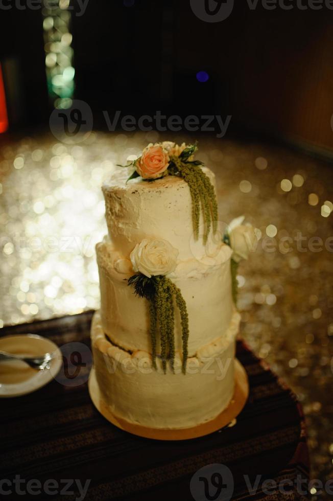 bolo de casamento em um fundo de um salão de casamento escuro. foto