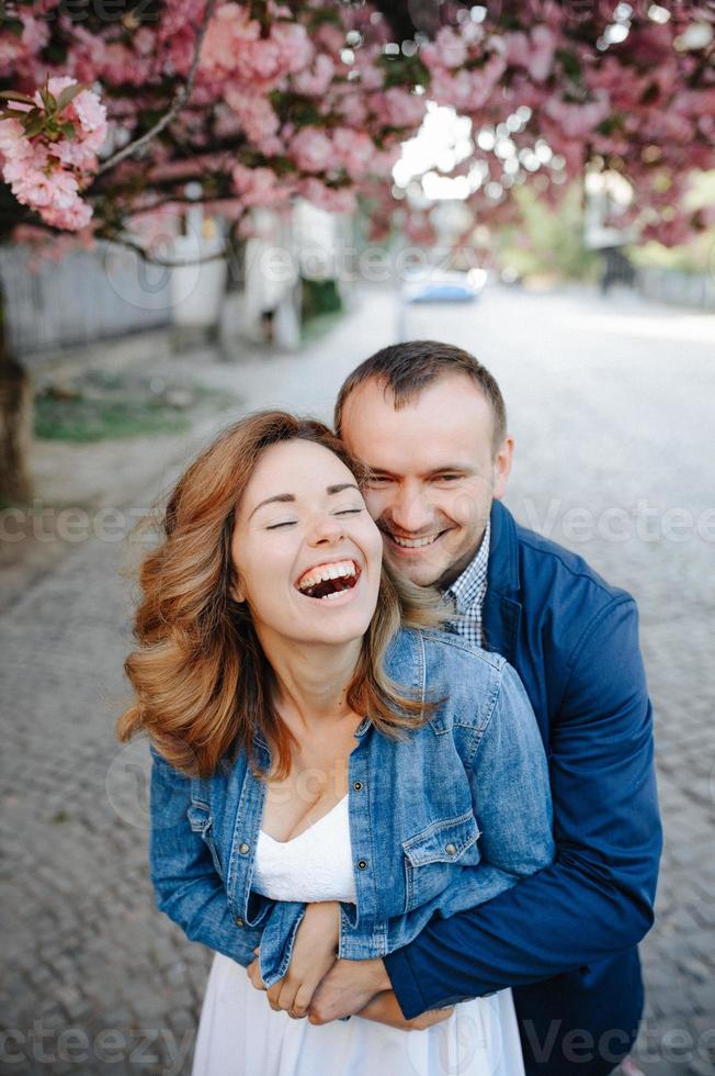 casal apaixonado em um pomar de macieiras florescendo deitado no cobertor foto