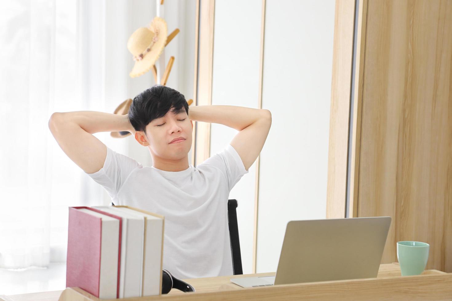 freelancer masculino asiático trabalhando em home office enquanto descansa os olhos na sala de estilo aconchegante com espaço de cópia foto