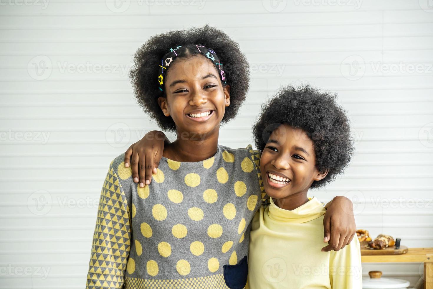 crianças felizes dois irmãos adoráveis e fofos crianças afro-americanas abraçam o pescoço e sorriem, a irmã mais velha abraça o irmãozinho pelo pescoço foto