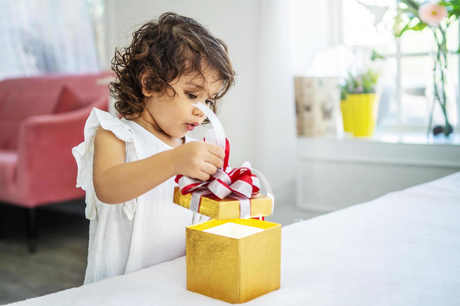 retrato de menina adorável abrindo o presente de caixa de aniversário e olhando para dentro com expressão facial alegre surpresa foto