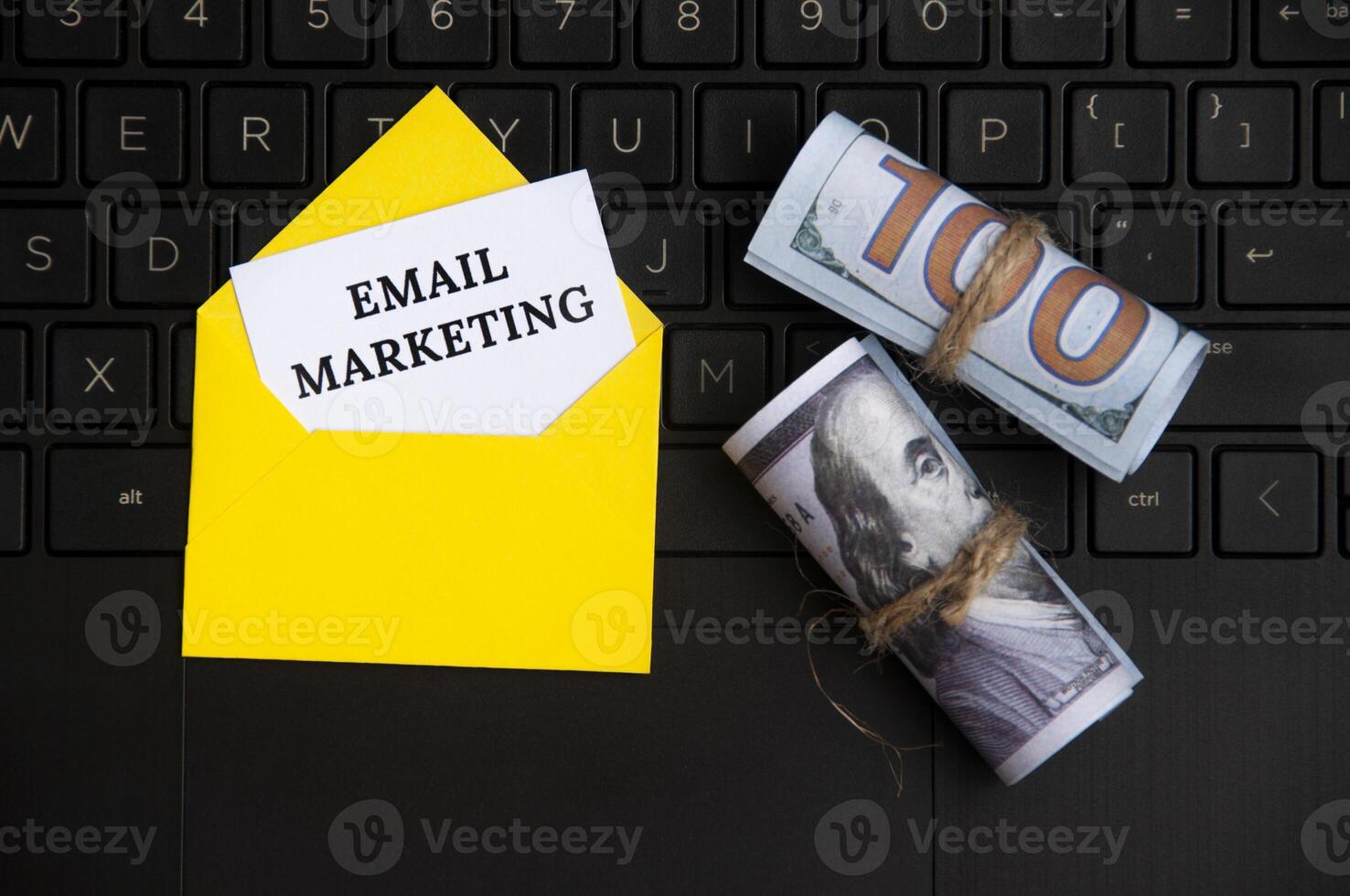 vista superior do texto de e-mail marketing no bloco de notas em um envelope com notas de banco e fundo do laptop. foto