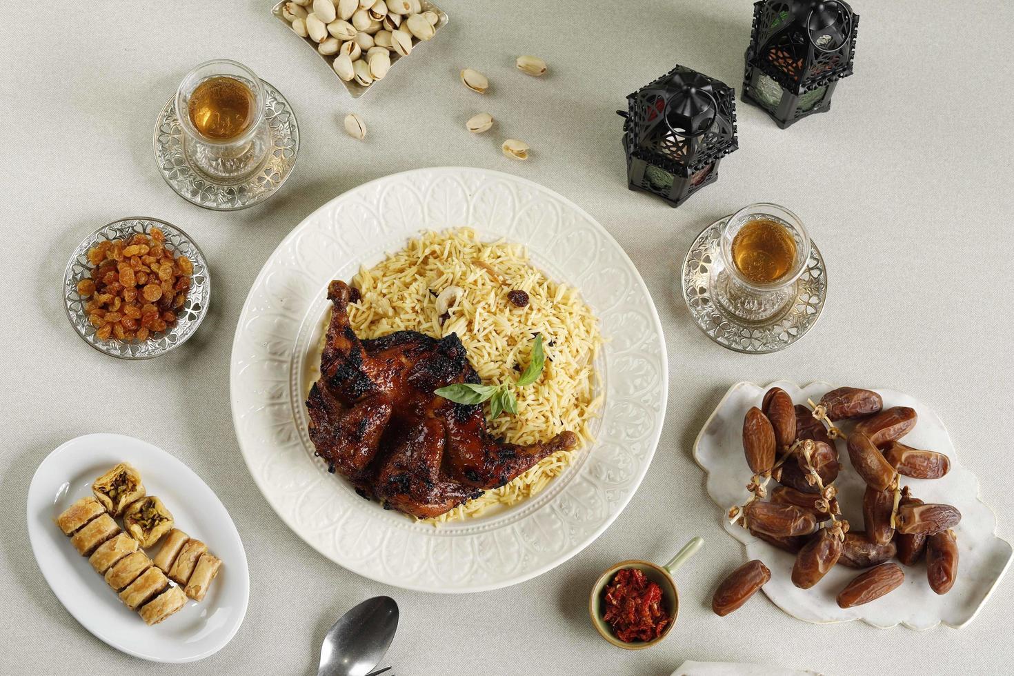 menu iftar do ramadã, kabsa de arroz basmati com frango assado, passas, chá, tâmaras, pistache e baklava turca foto